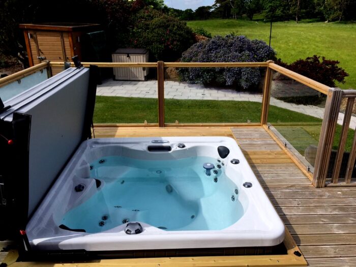 Marquis Spas Celebrity Broadway Hot Tub sunken in a decking with cover open
