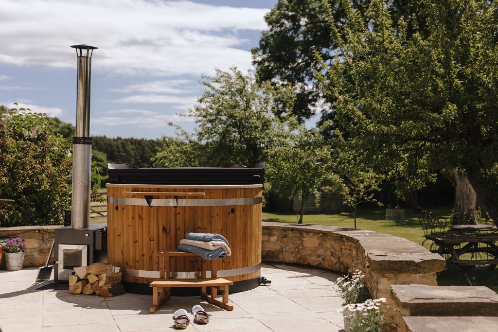 A Kirami Wood fired hot tub on a patio in the sunshine